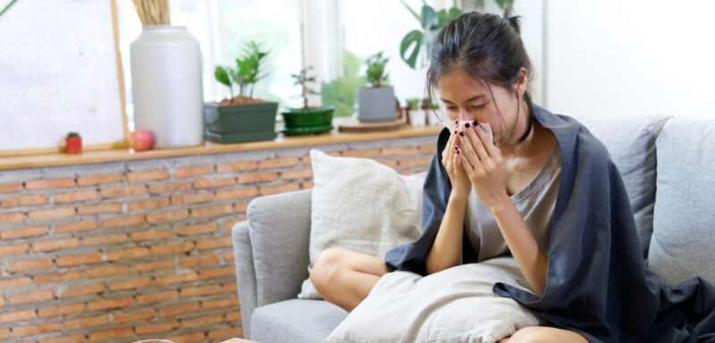 Seorang wanita sedang mengalami flu dan batuk