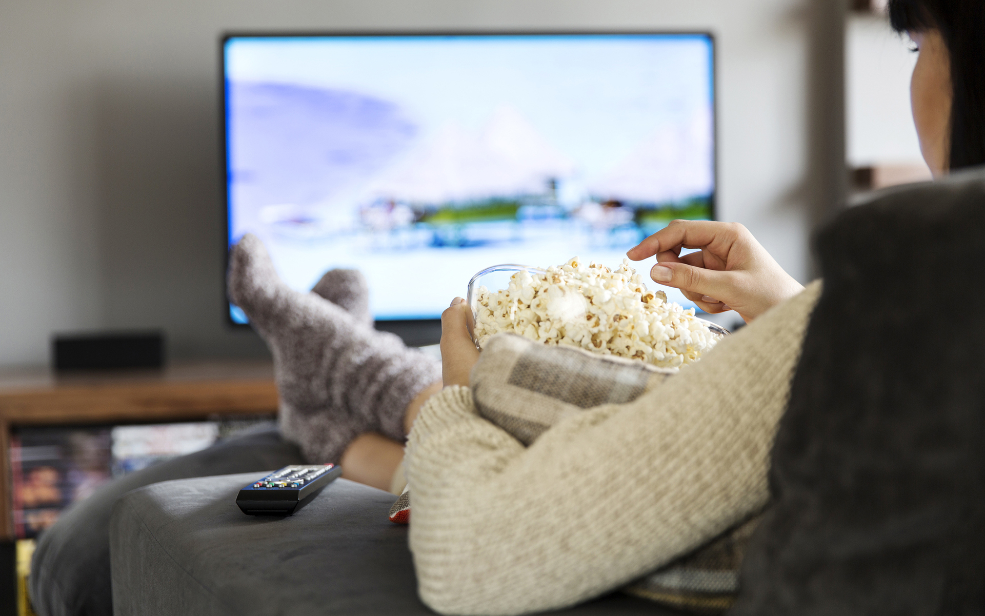 Woman watching TV and eating popcorn